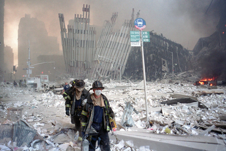 Firefighters walk away from crumbling towers.